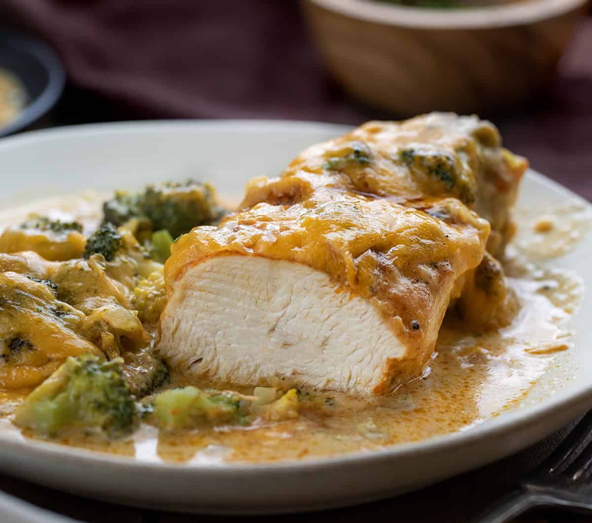 Piece of Broccoli Cheddar Chicken on a plate on a wooden table and the piece has been cut Piece of Broccoli Cheddar Chicken on a plate on a wooden table and the piece has been cut.