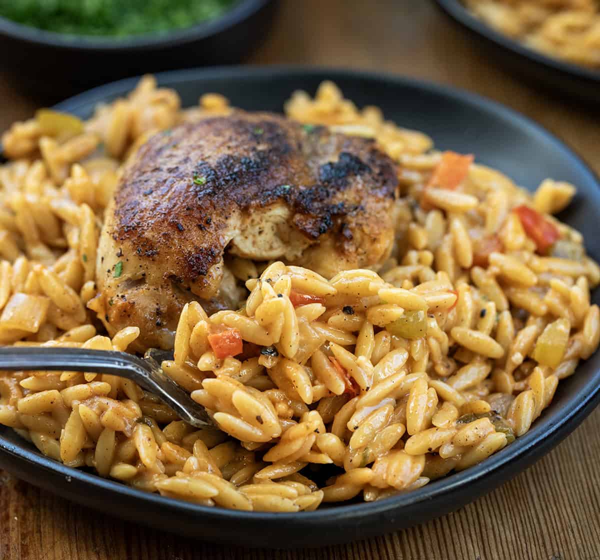 Forkful of creamy cajun orzo being held in front of the chicken Forkful of creamy cajun orzo being held in front of the chicken.