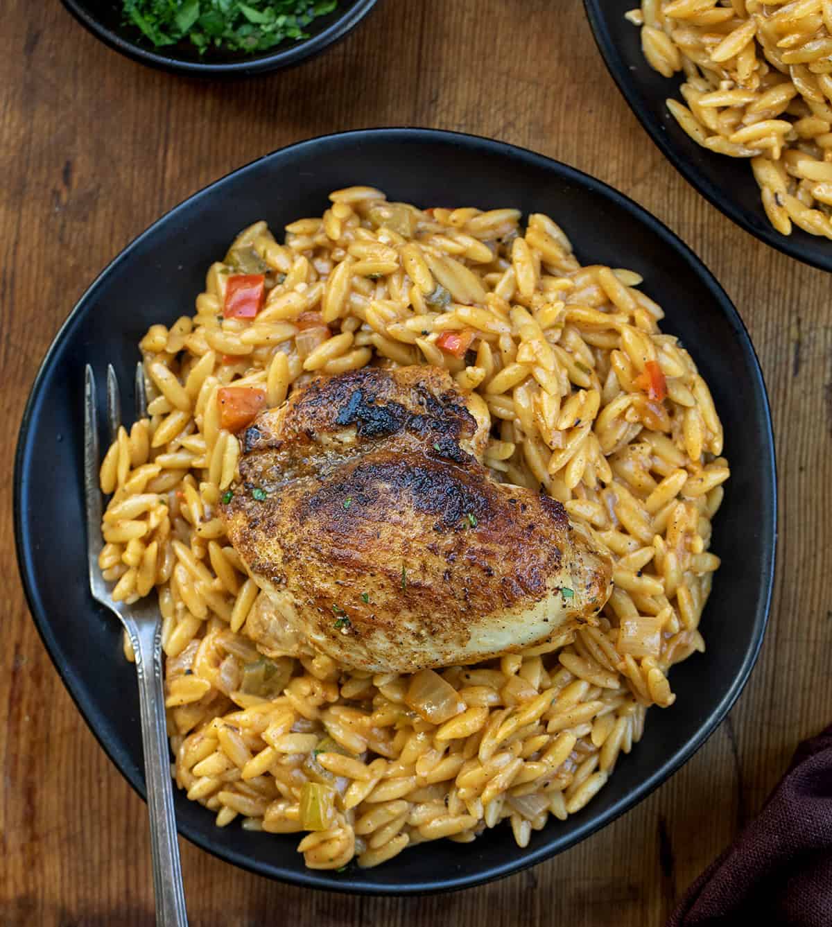 Cajun Chicken Orzo on a black plate on a wooden table from overhead Cajun Chicken Orzo on a black plate on a wooden table from overhead.