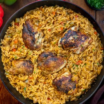 Skillet of Cajun Chicken Orzo on a wooden table from overhead.