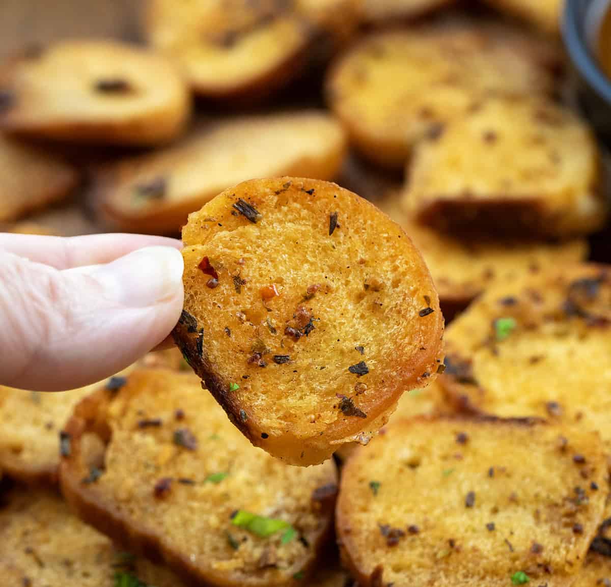 Hand holding one Cowboy Butter Bagel Chip.
