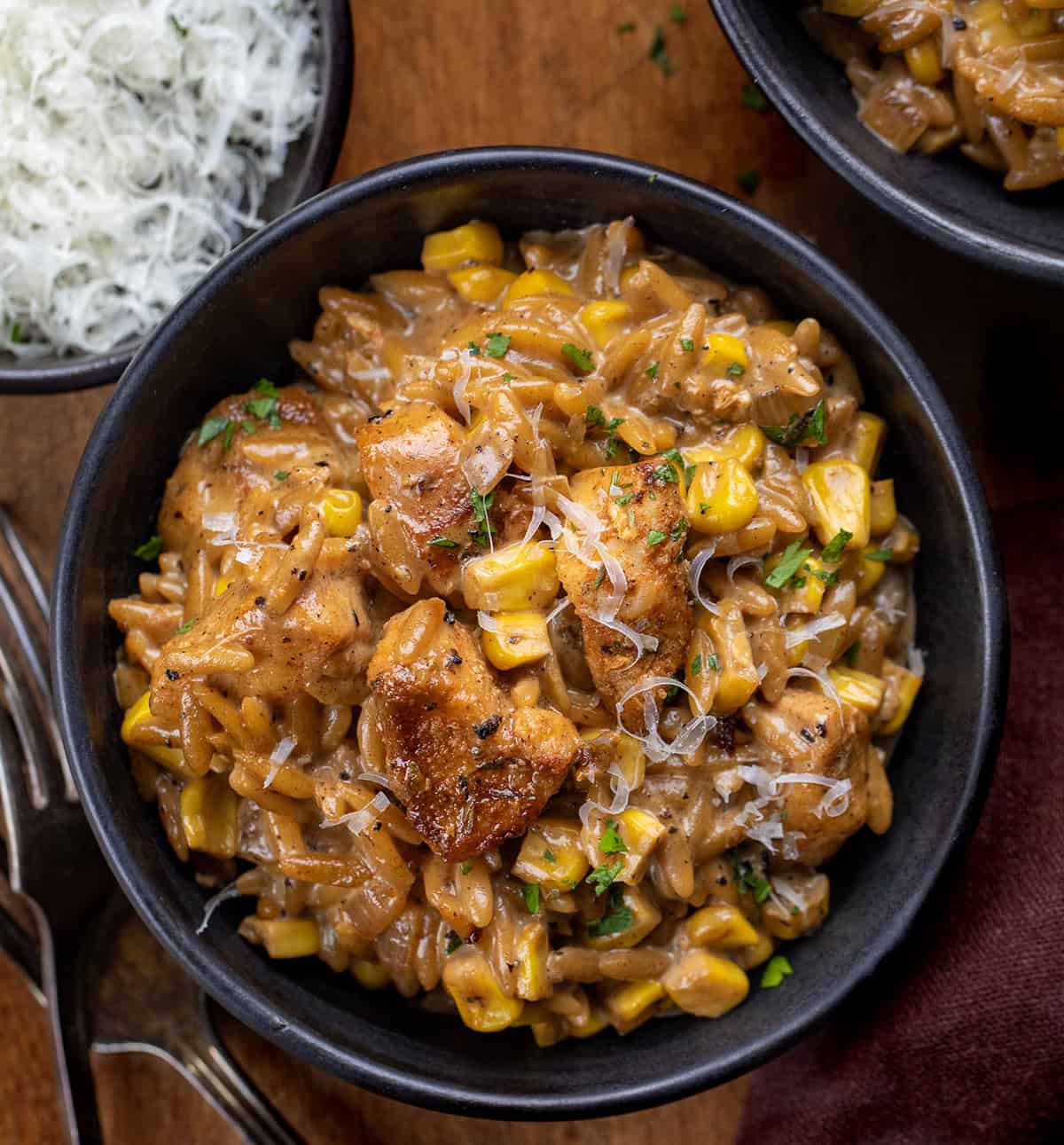 Bowls of Creamed Corn Orzo with Chicken on a wooden table from overhead Bowls of Creamed Corn Orzo with Chicken on a wooden table from overhead.