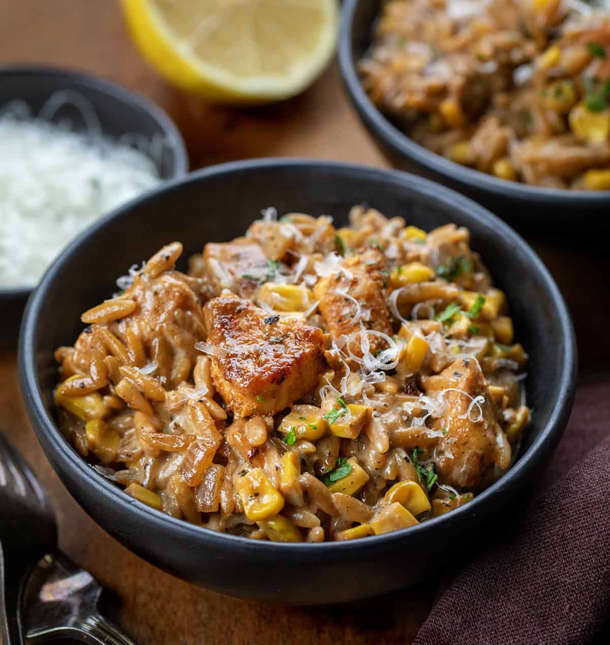 Bowls of Creamed Corn Orzo with Chicken on a wooden table from parmesan Bowls of Creamed Corn Orzo with Chicken on a wooden table from parmesan.