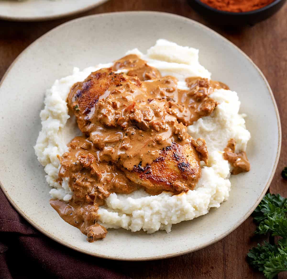 Creamy Paprika Chicken on mashed potatoes on a plate on a wooden table Creamy Paprika Chicken on mashed potatoes on a plate on a wooden table.
