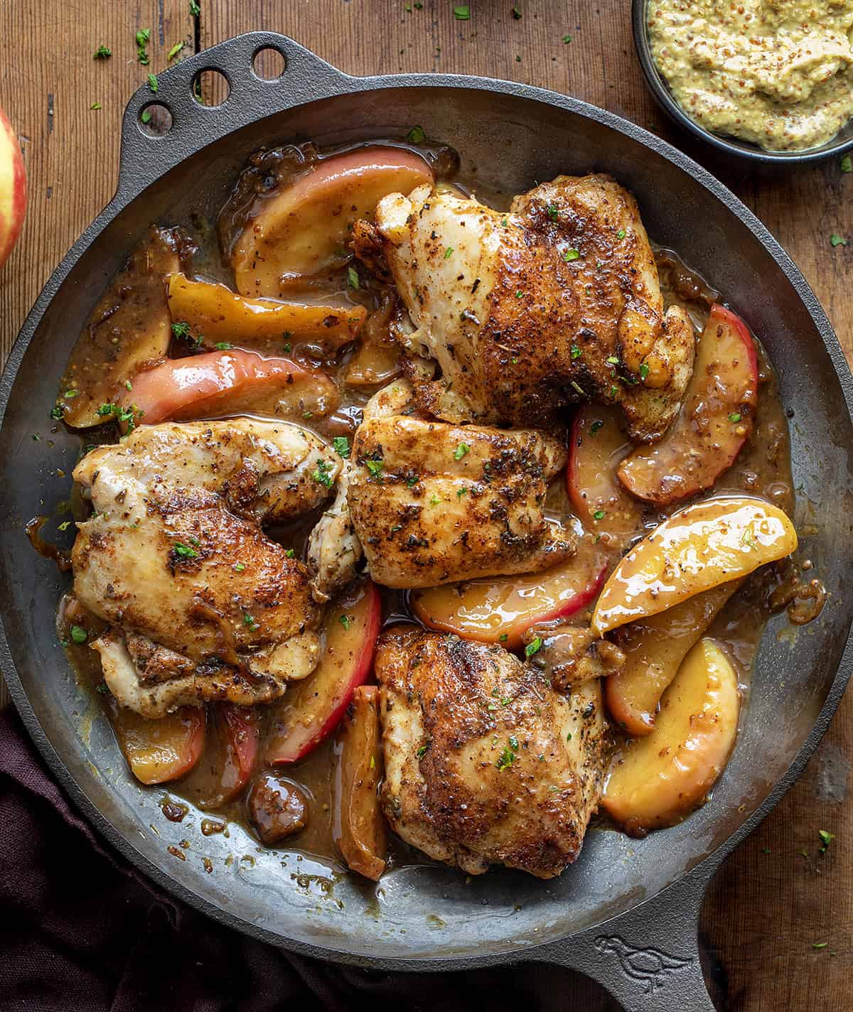 Skillet of Dijon Apple Shallot Chicken on a wooden table from overhead Skillet of Dijon Apple Shallot Chicken on a wooden table from overhead.