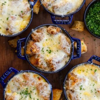 Small blue crocks of French Onion Soup with croutons and melted cheese from overhead on a wooden table.