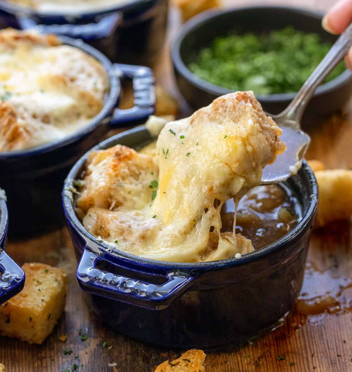 Spoon picking up a bite of croutons and melted cheese from a small bowl Spoon picking up a bite of croutons and melted cheese from a small bowl.