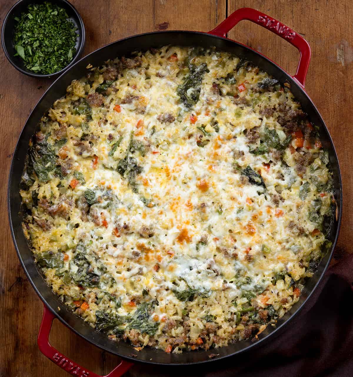 Red skillet filled with Italian Sausage and Rice on a wooden table from overhead Red skillet filled with Italian Sausage and Rice on a wooden table from overhead.