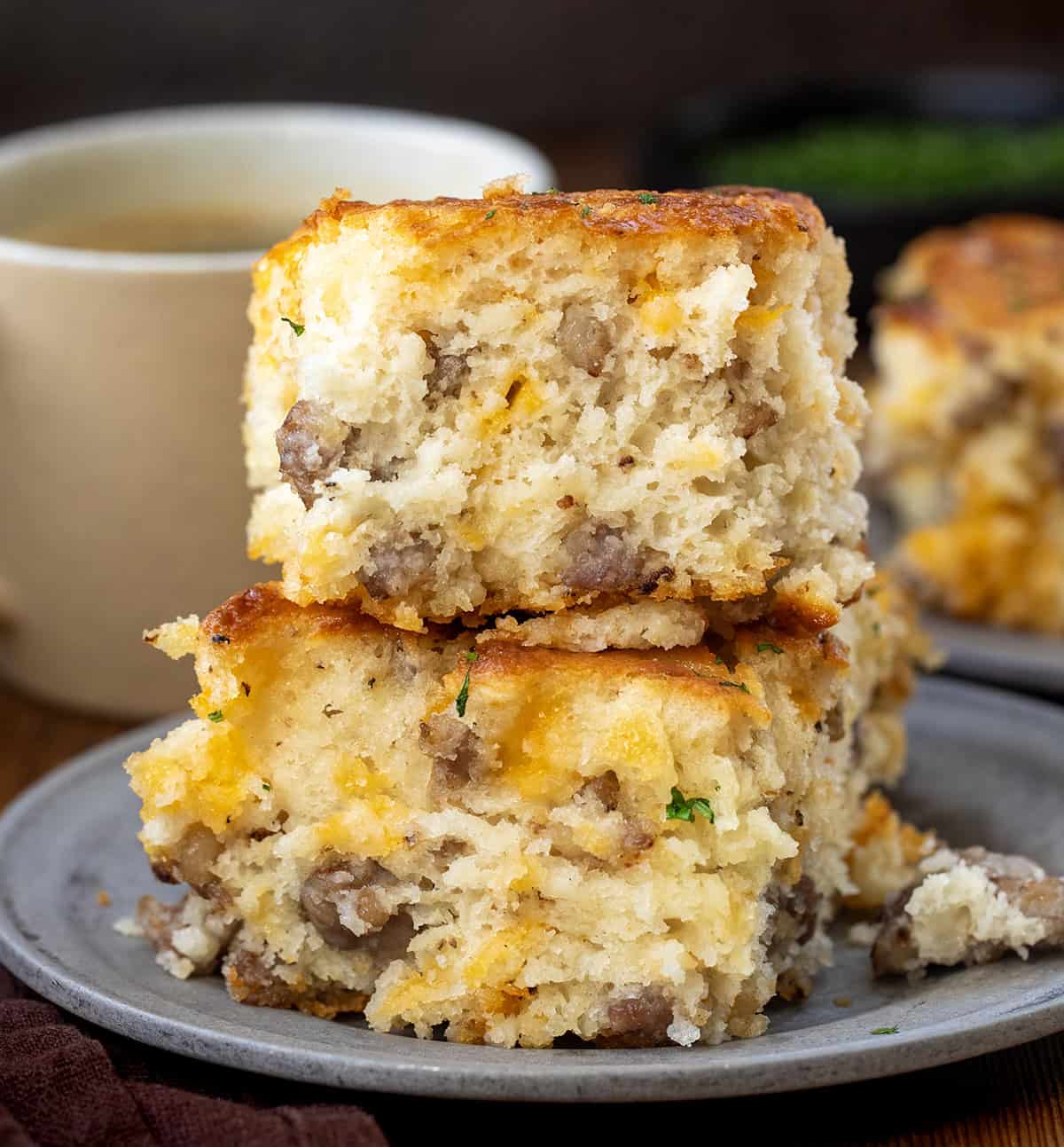 Stack of Maple Sausage Butter Swim Biscuits on a plate with coffee in the background Stack of Maple Sausage Butter Swim Biscuits on a plate with coffee in the background.