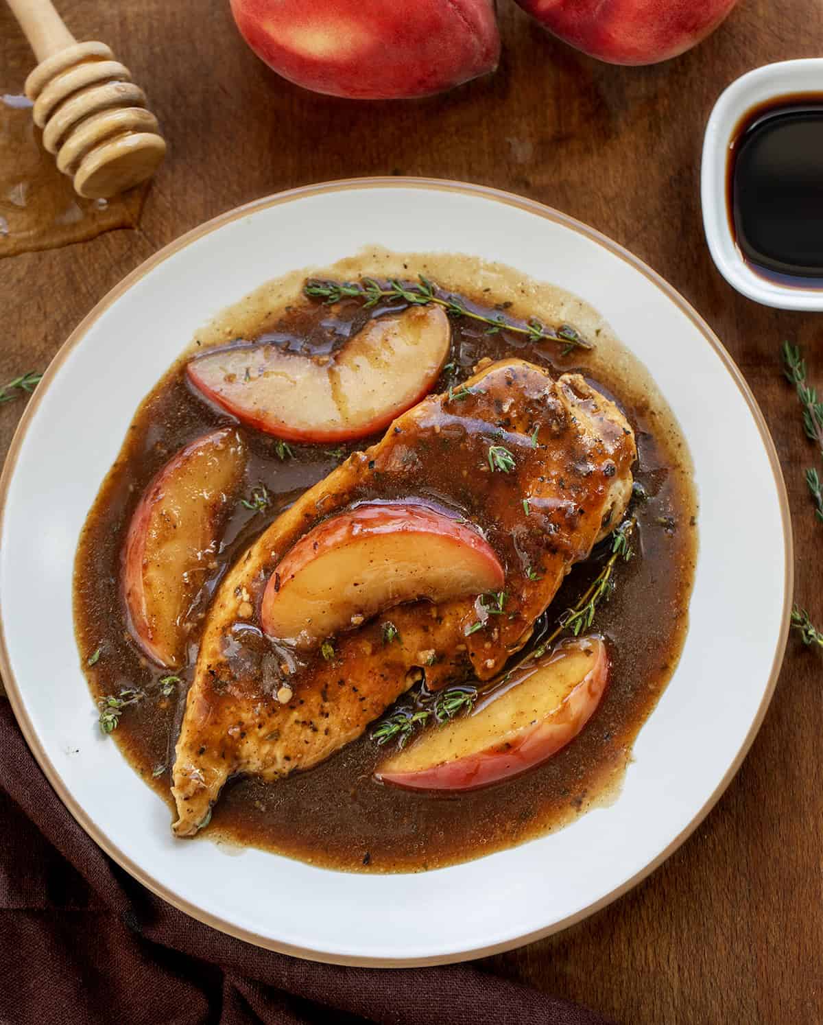 Peach Balsamic Chicken on a white plate on a wooden table from overhead Peach Balsamic Chicken on a white plate on a wooden table from overhead.