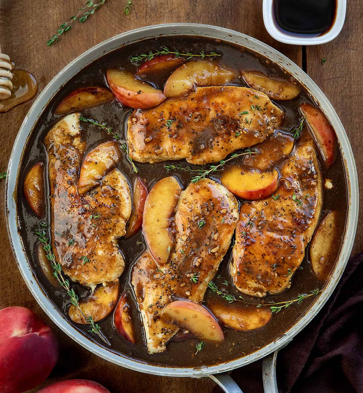 Peach Balsamic Chicken in a skillet on a wooden table from overhead Peach Balsamic Chicken in a skillet on a wooden table from overhead.