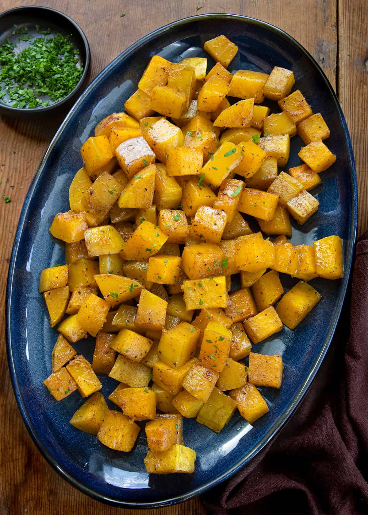 Blue serving platter filled with Roasted Butternut Squash on a wooden table from overhead Blue serving platter filled with Roasted Butternut Squash on a wooden table from overhead.