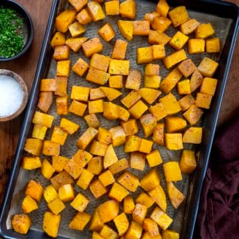Sheet pan of Roasted Butternut Squash on a wooden table from overhead.