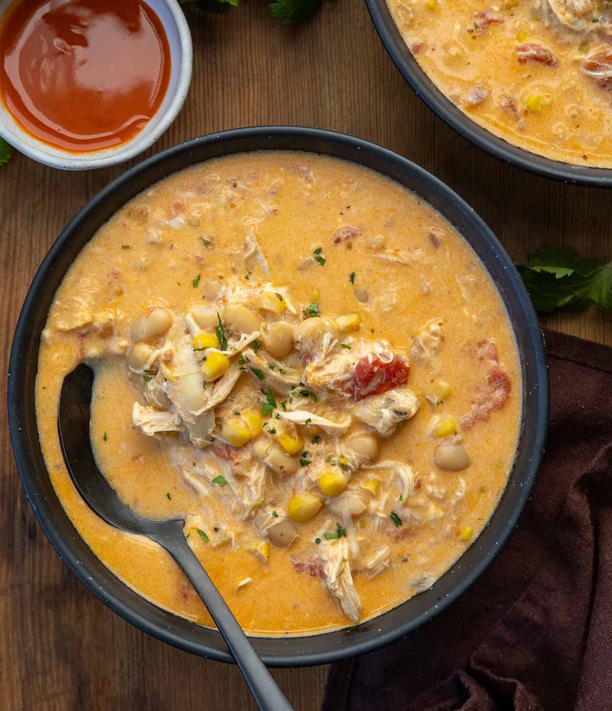 Bowls of Slow Cooker Buffalo Chicken Soup on a wooden table with one bowl with a spoon in it Bowls of Slow Cooker Buffalo Chicken Soup on a wooden table with one bowl with a spoon in it.