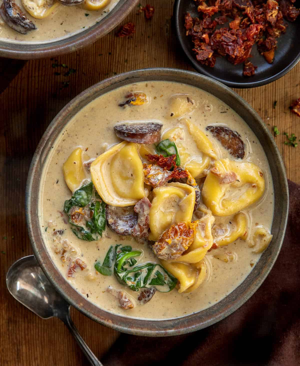 Bowls of Slow Cooker Kielbasa Tortellini Soup on a wooden table from overhead Bowls of Slow Cooker Kielbasa Tortellini Soup on a wooden table from overhead.