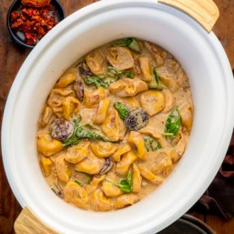 Slow Cooker Kielbasa Tortellini Soup on a wooden table from overhead.