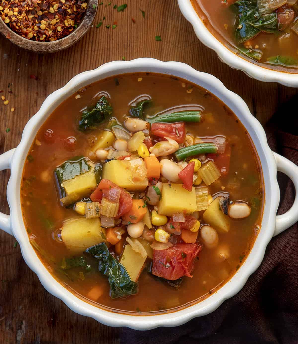 White bowls of Vegetable Soup on a wooden table from overhead White bowls of Vegetable Soup on a wooden table from overhead.
