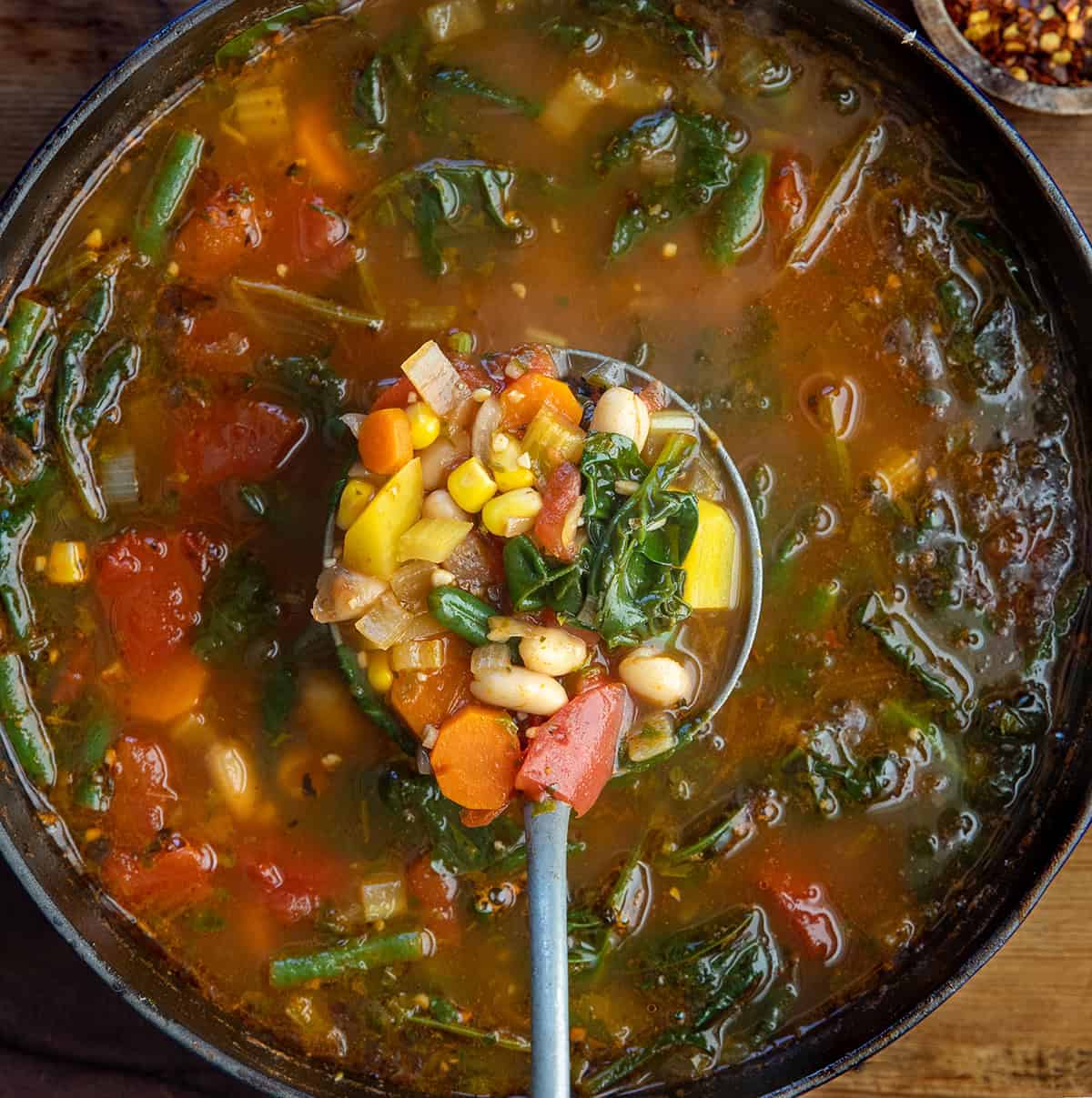 Pot of Vegetable Soup with a ladle full being held above the pot Pot of Vegetable Soup with a ladle full being held above the pot.