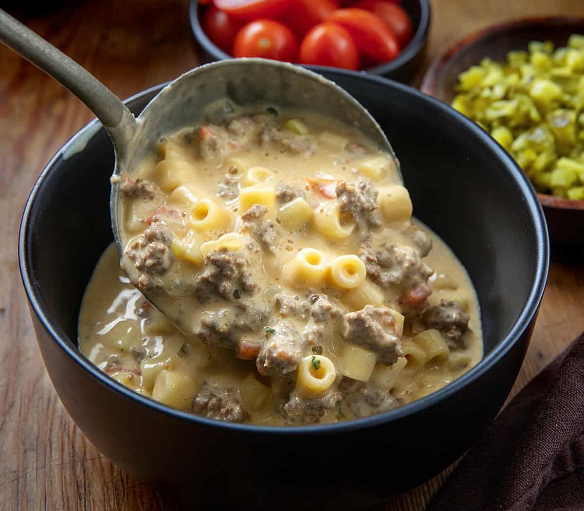 Ladeling Cheeseburger Pasta Soup into a black bowl Ladeling Cheeseburger Pasta Soup into a black bowl.