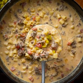 Ladle full of Cheeseburger Pasta Soup being held above the pot.