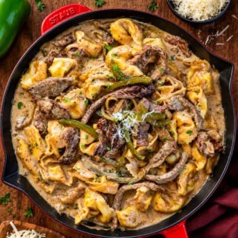 Skillet of Cheesesteak Tortellini on a wooden table from overhead.
