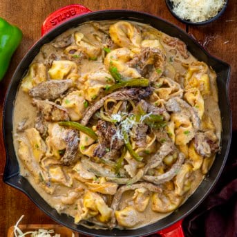 Skillet of Cheesesteak Tortellini on a wooden table from overhead.