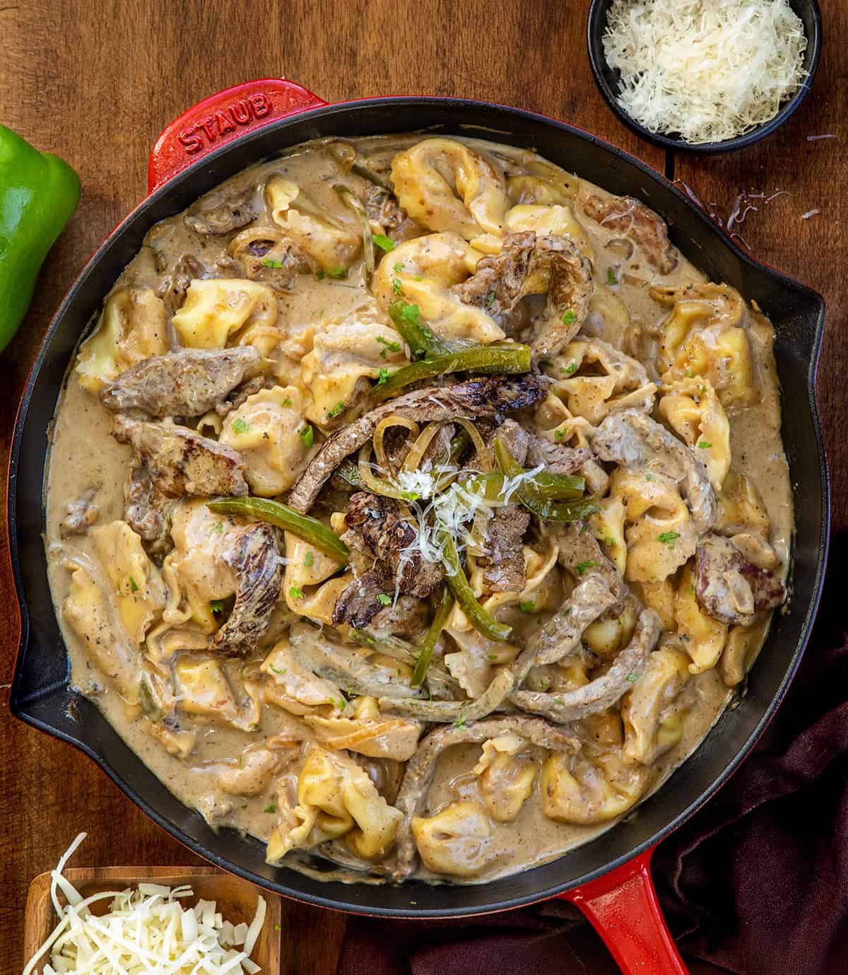 Skillet of Cheesesteak Tortellini on a wooden table from overhead Skillet of Cheesesteak Tortellini on a wooden table from overhead.