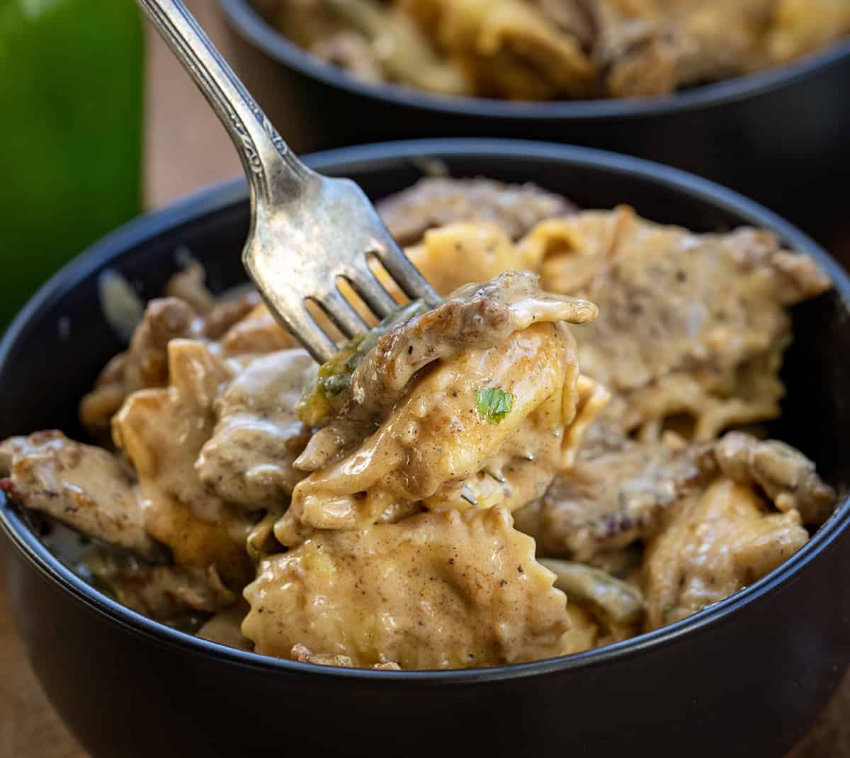 Forkful of Cheesesteak Tortellini being held above a bowl Forkful of Cheesesteak Tortellini being held above a bowl.
