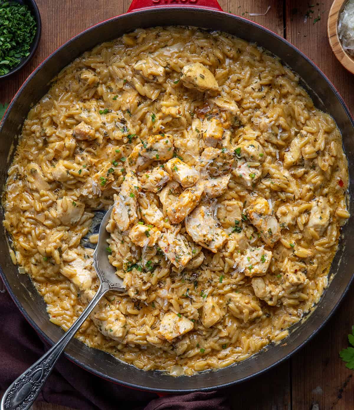 Skillet of Cowboy Butter Chicken Orzo on a wooden table from overhead Skillet of Cowboy Butter Chicken Orzo on a wooden table from overhead.