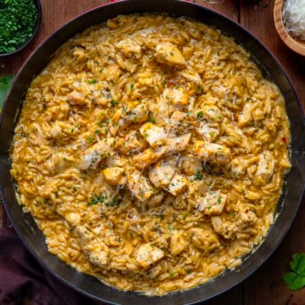 Skillet of Cowboy Butter Chicken Orzo on a wooden table from overhead.