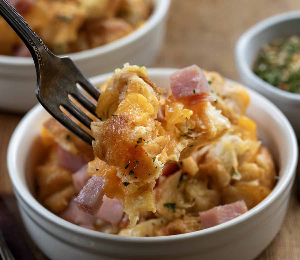 Forkful of Cowboy Butter Ham and Cheese Croissant Bake being held above the bowl.