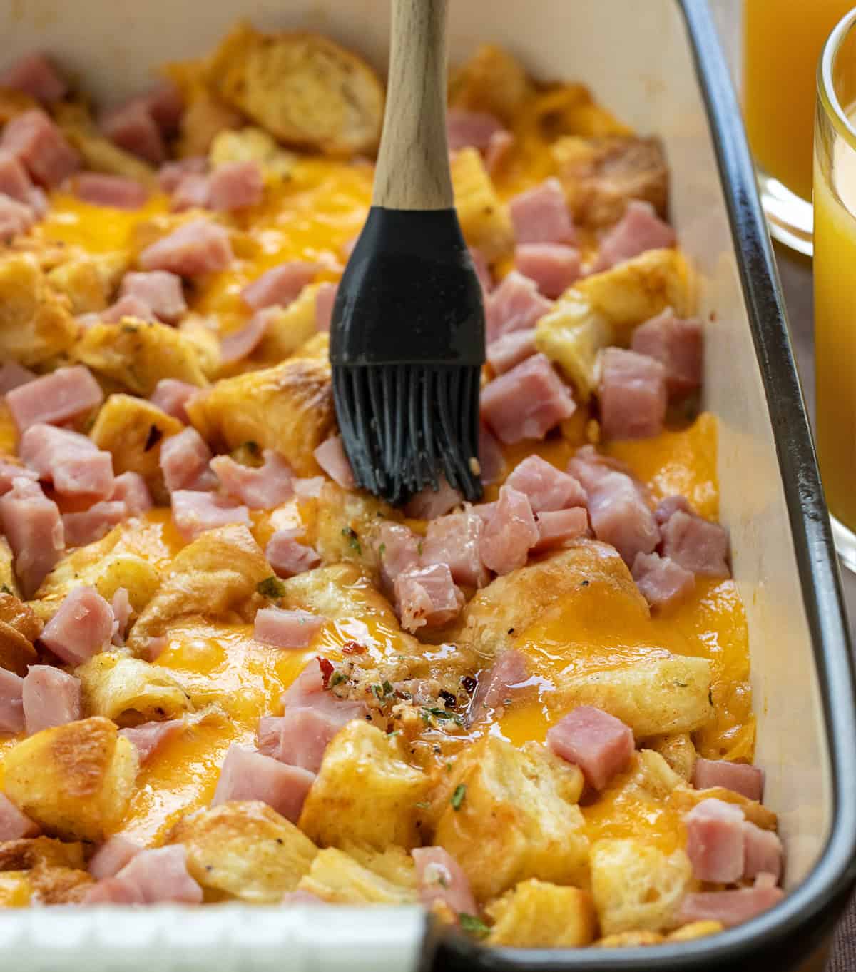 Brushing Cowboy Butter over Ham and Cheese Croissant Bake.