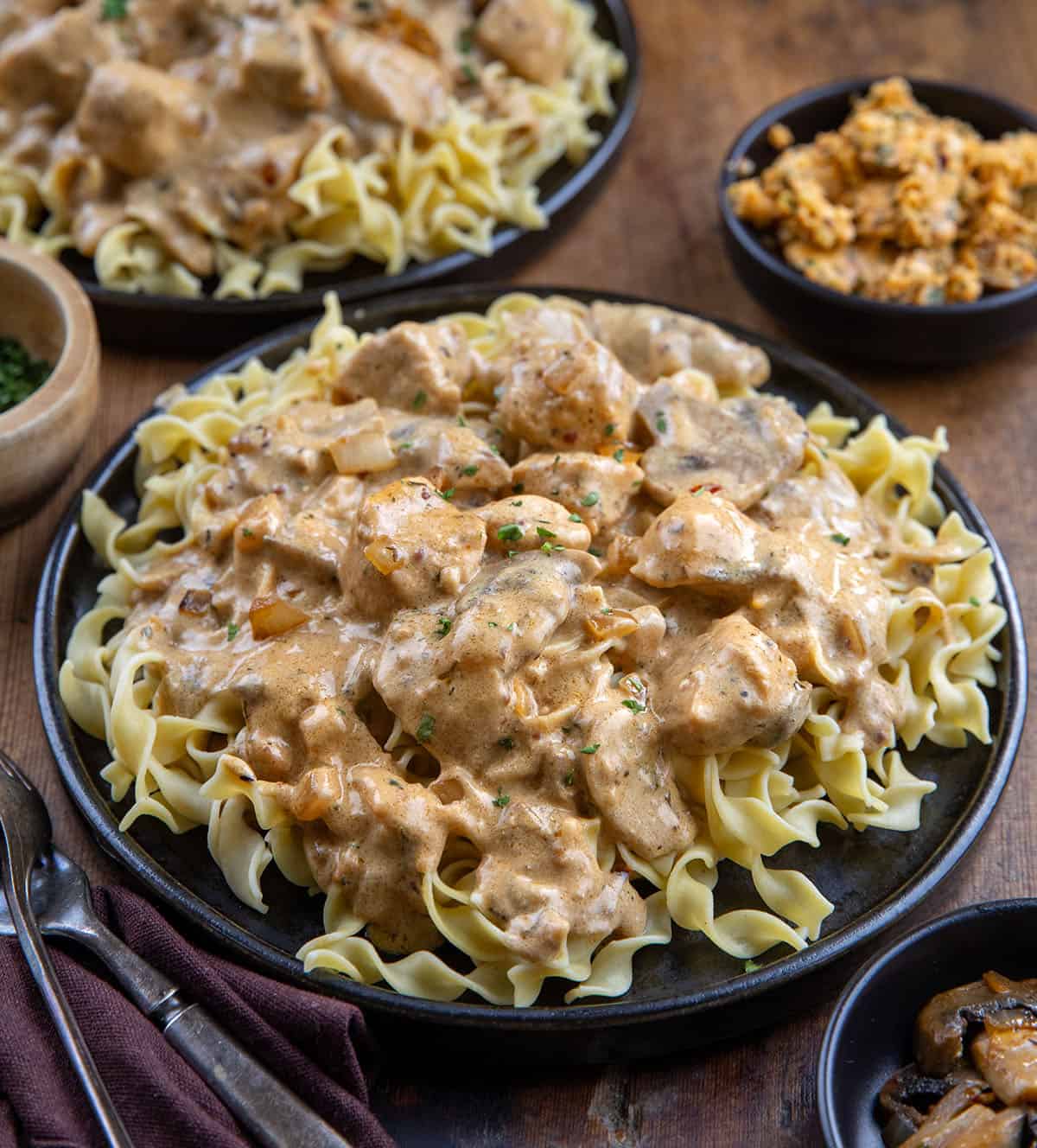 Plates of Cowboy Chicken Stroganoff on a wooden table next to cowboy butter Plates of Cowboy Chicken Stroganoff on a wooden table next to cowboy butter.
