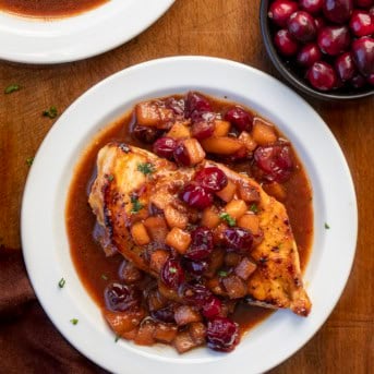 White plates with Cranberry Apple Chicken on them on a wooden table.