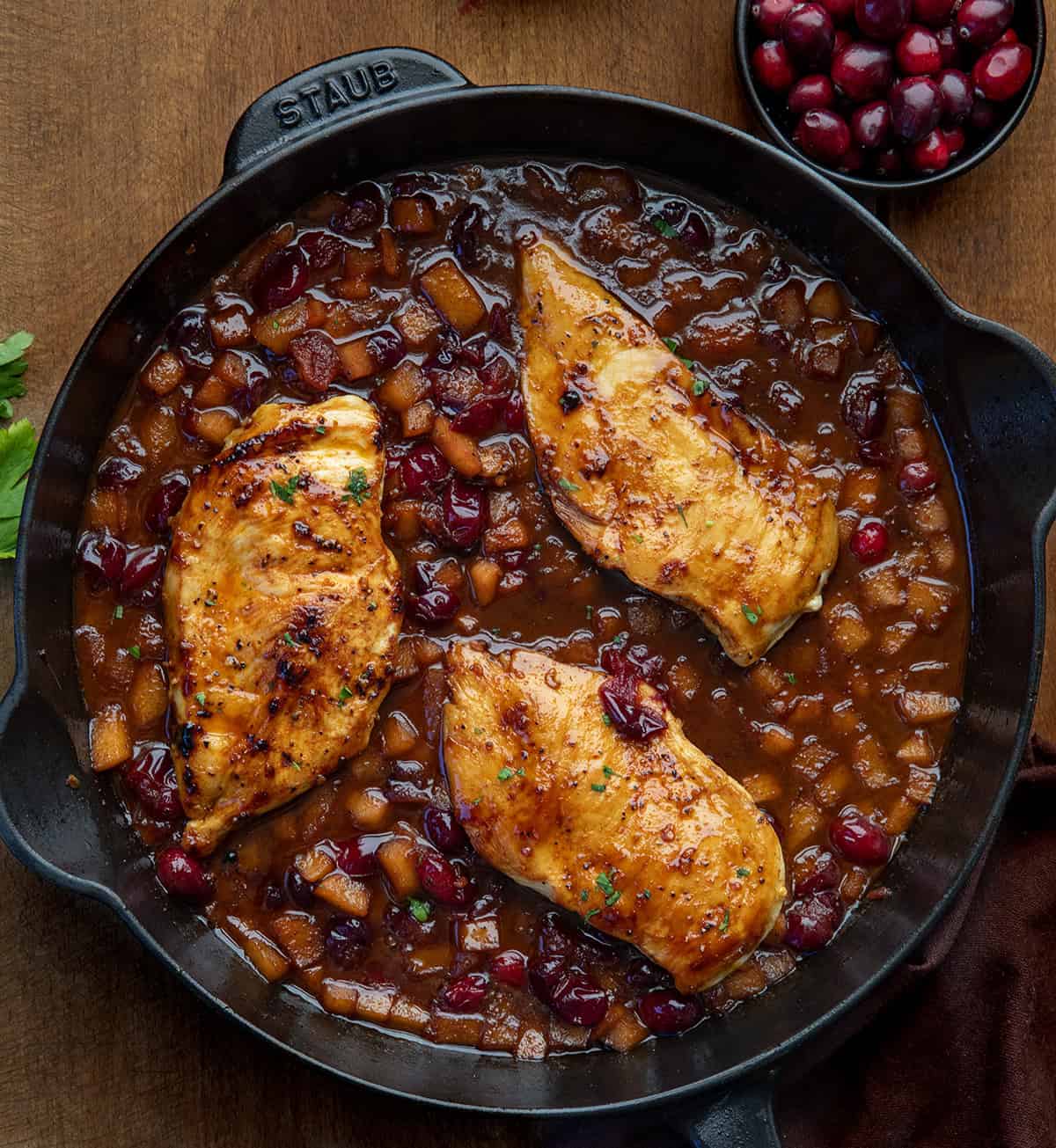 Cranberry Apple Chicken in a skillet on a wooden table from overhead Cranberry Apple Chicken in a skillet on a wooden table from overhead.