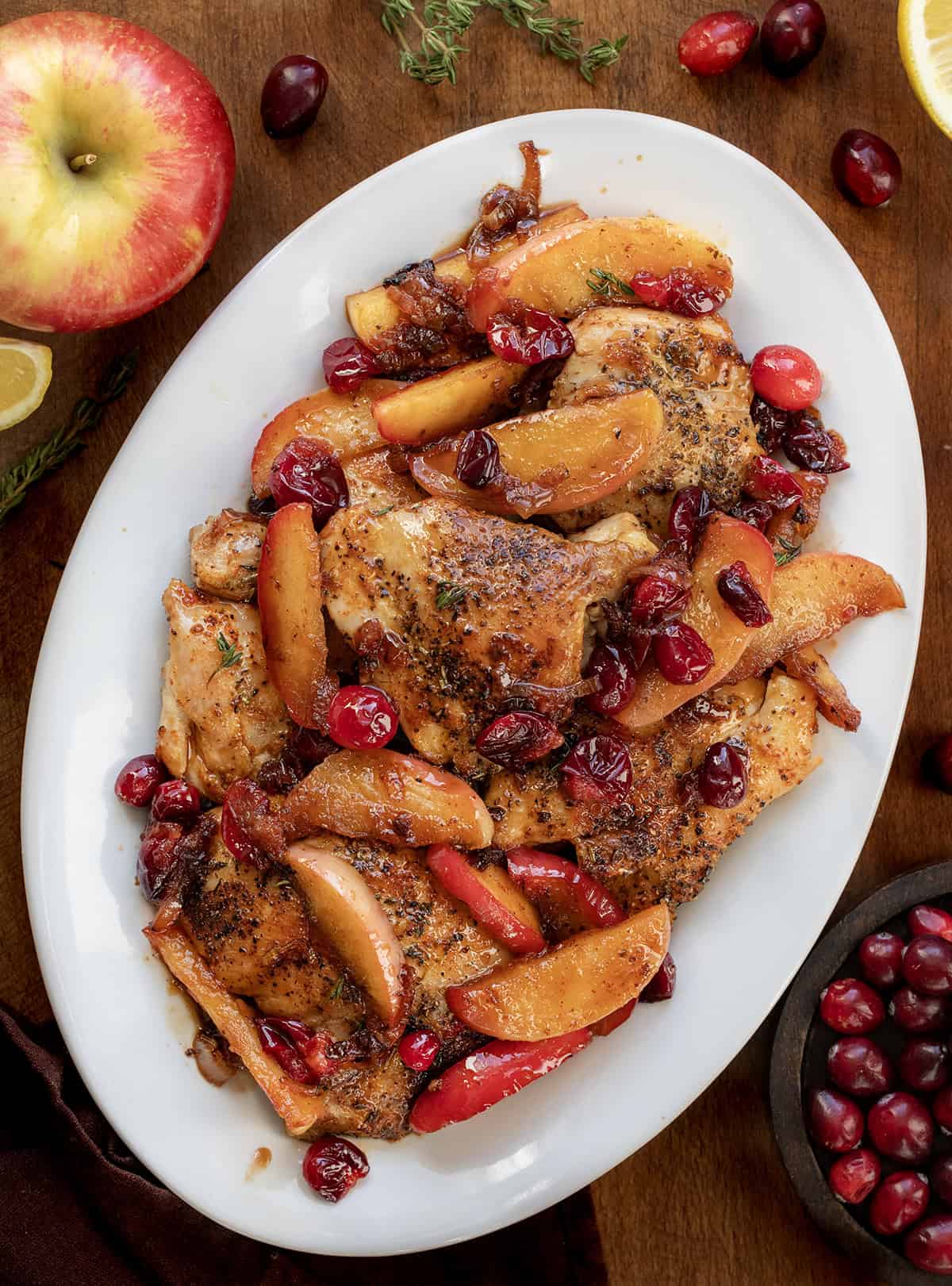 White platter of Cranberry Apple Orchard Chicken on a wooden table from overhead White platter of Cranberry Apple Orchard Chicken on a wooden table from overhead.