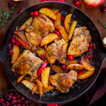 Skillet of Cranberry Apple Orchard Chicken on a wooden table from overhead.