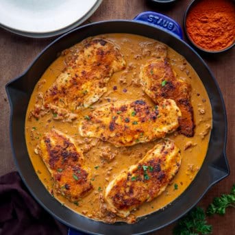 Skillet of Creamy Paprika Chicken on a wooden table from overhead.