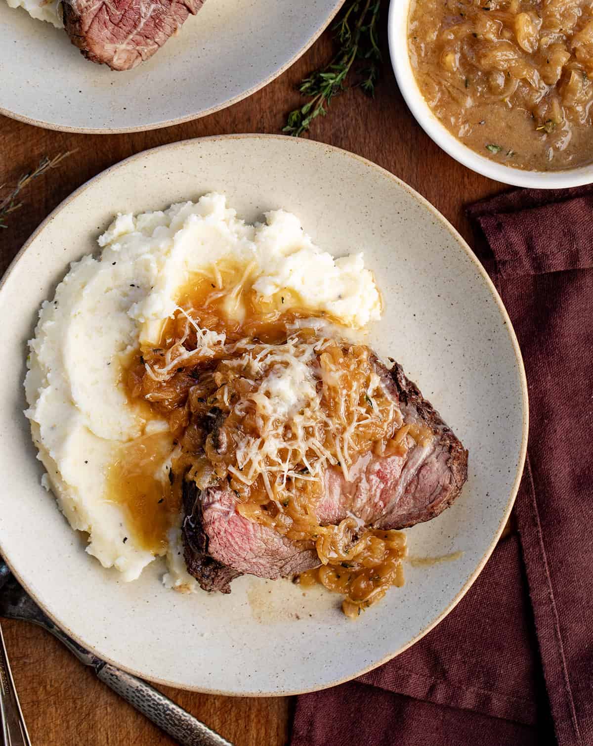 Plates of French Onion Beef Tenderloin on a wooden table from overhead Plates of French Onion Beef Tenderloin on a wooden table from overhead.