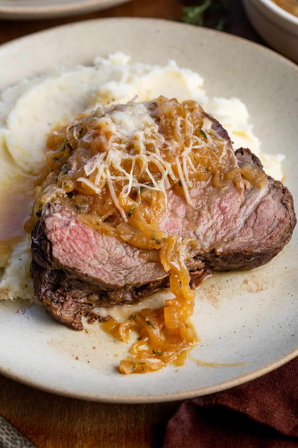 Close up of slice of French Onion Beef Tenderloin on a plate on a wooden table Close up of slice of French Onion Beef Tenderloin on a plate on a wooden table.