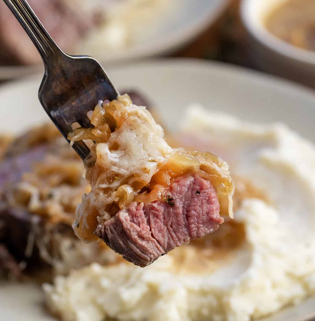 Close up of a forkful of beef tenderloin with french onions and cheese Close up of a forkful of beef tenderloin with french onions and cheese.