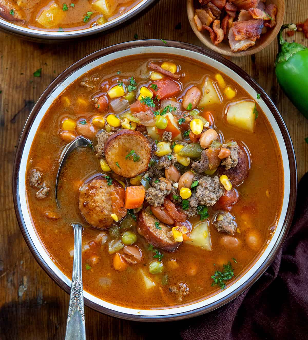 Bowls of Green Chili Cowboy Stew on a wooden table from overhead Bowls of Green Chili Cowboy Stew on a wooden table from overhead.