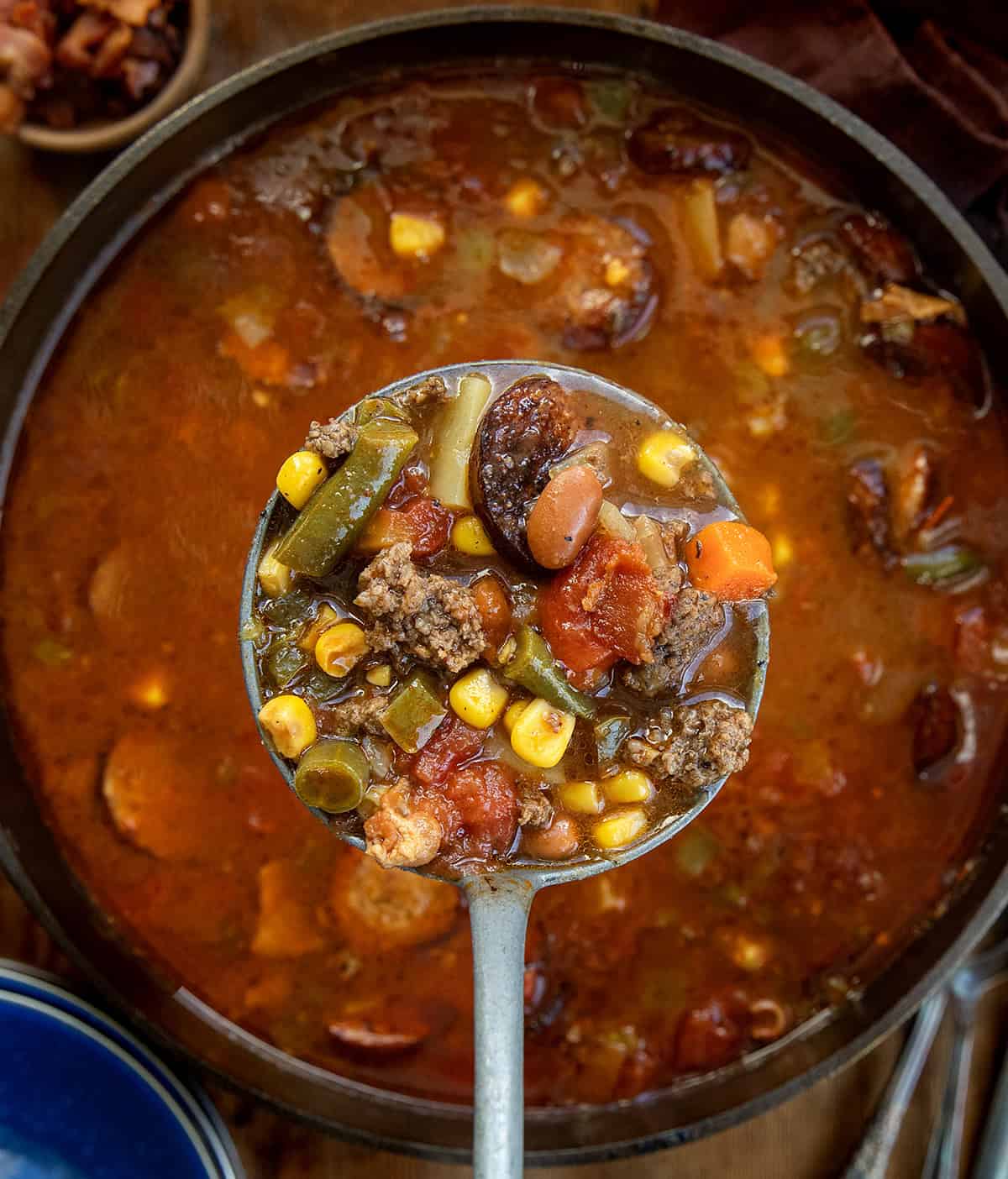 Pot of Green Chili Cowboy Stew with a ladle held above it filled with soup Pot of Green Chili Cowboy Stew with a ladle held above it filled with soup.