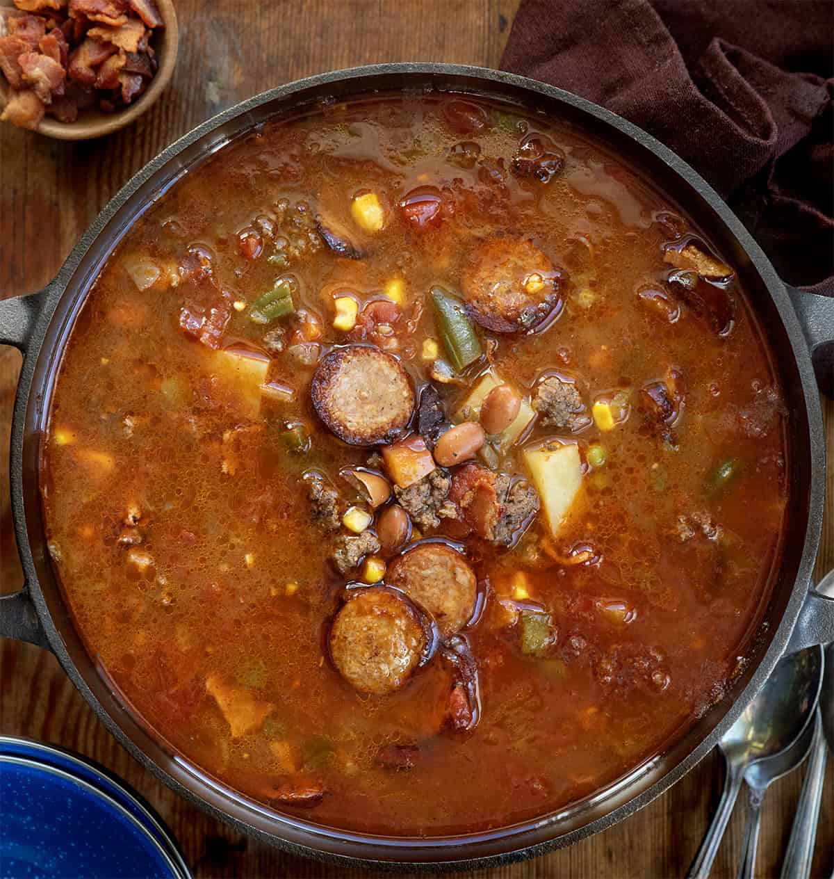 Pot of Green Chili Cowboy Stew on a wooden table from overhead Pot of Green Chili Cowboy Stew on a wooden table from overhead.