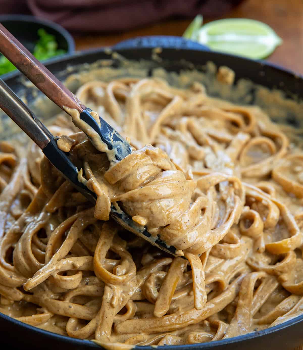 Using a tongs to pick up creamy Jerk Chicken Alfredo Pasta from the pan Using a tongs to pick up creamy Jerk Chicken Alfredo Pasta from the pan.