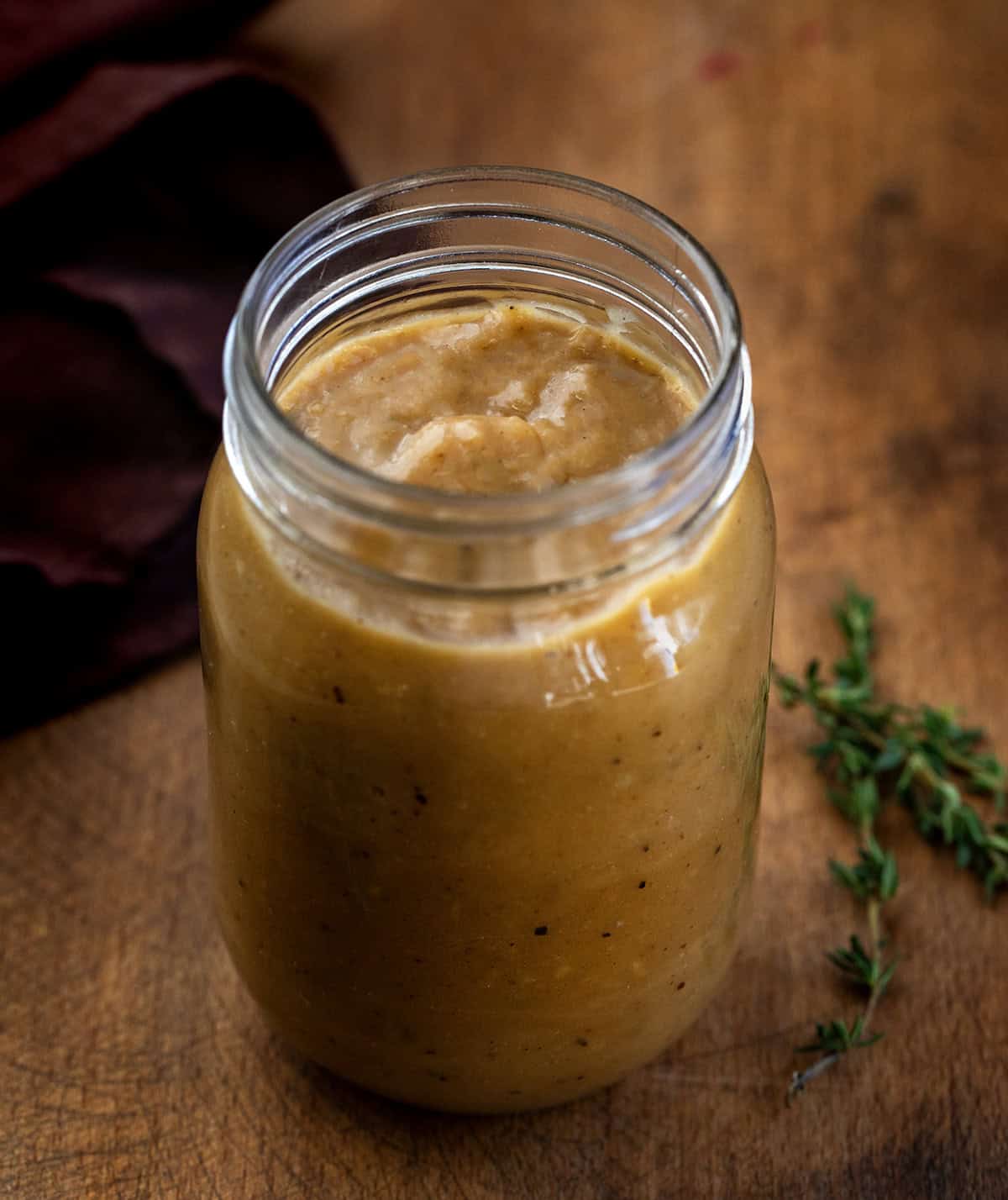 Jar of Make-Ahead Turkey Gravy on a wooden table Jar of Make-Ahead Turkey Gravy on a wooden table.