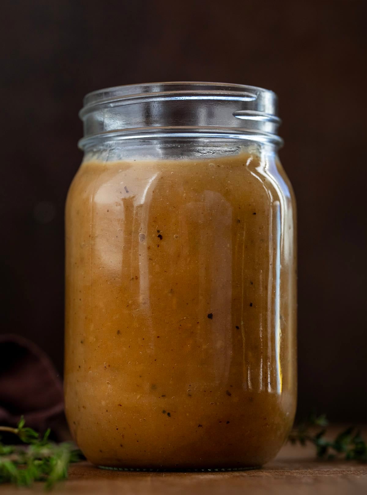 Jar of Make-Ahead Turkey Gravy on a wooden table Jar of Make-Ahead Turkey Gravy on a wooden table.