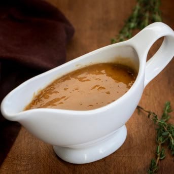 Gravy boat filled with Make-Ahead Turkey Gravy on a wooden table.