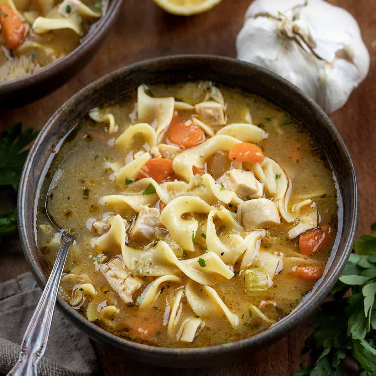Bowls of Roasted Garlic Chicken Noodle Soup on a wooden table Bowls of Roasted Garlic Chicken Noodle Soup on a wooden table.