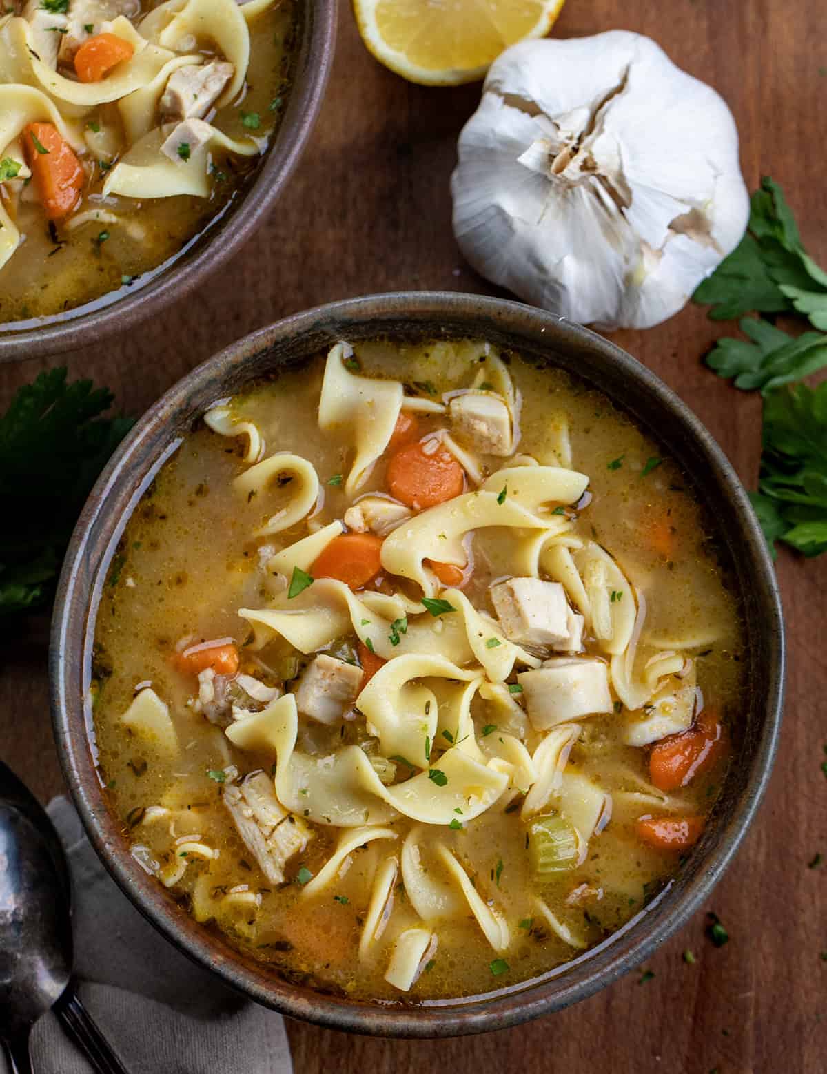 Bowls of Roasted Garlic Chicken Noodle Soup on a wooden table from overhead Bowls of Roasted Garlic Chicken Noodle Soup on a wooden table from overhead.